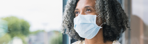 Woman wearing mask looking out window